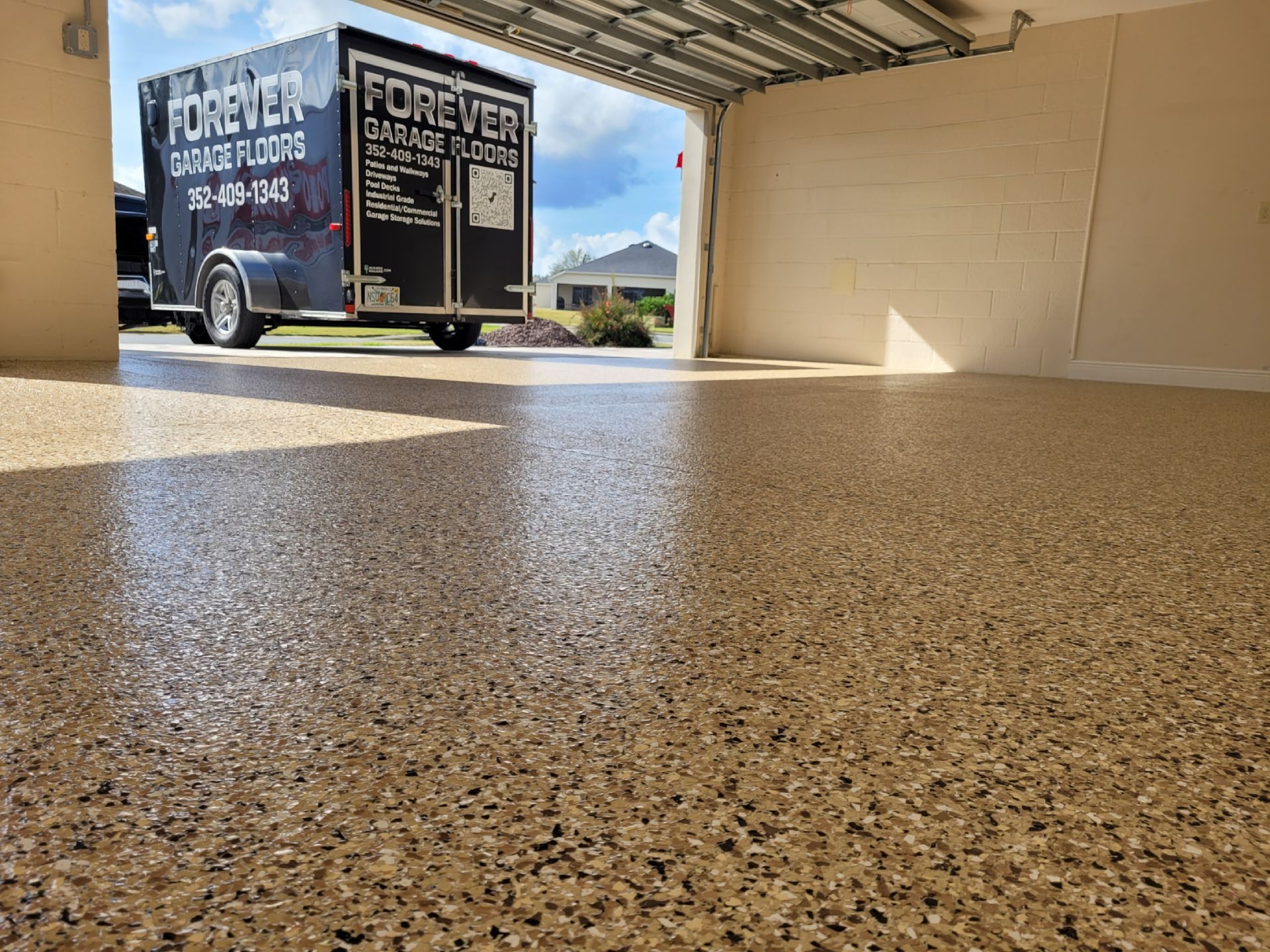 Garage with a speckled epoxy floor. A trailer with