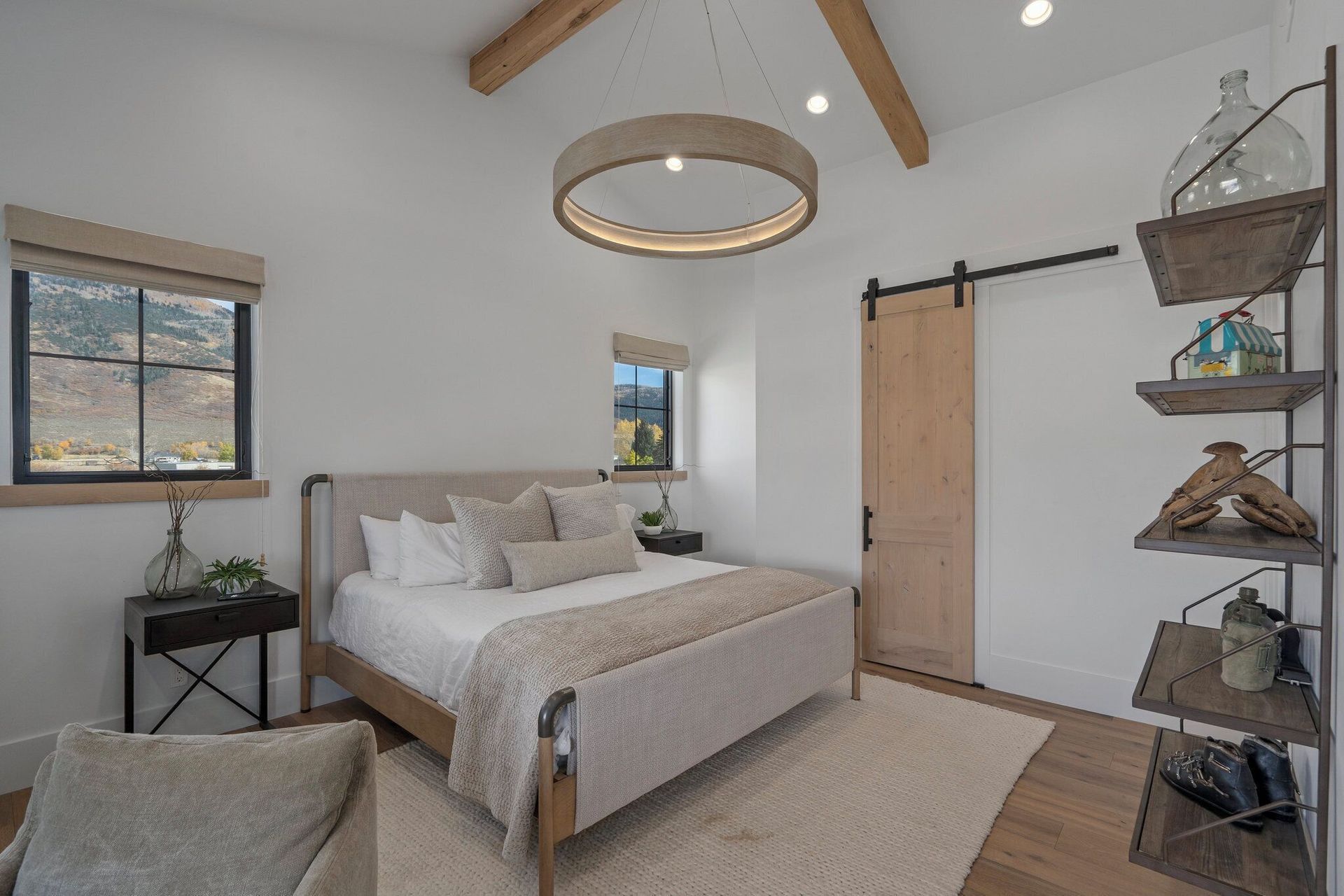 Bedroom with bed, accent chair, sliding door, shelving, neutral colors.