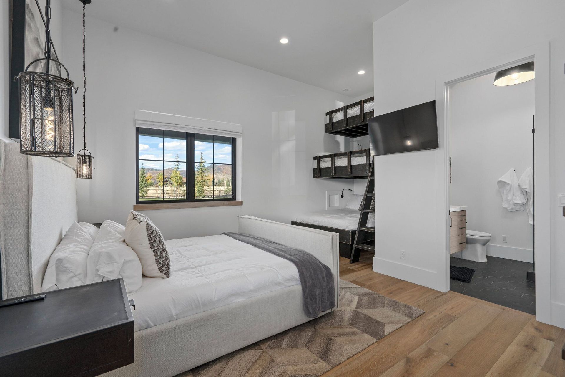 Bedroom with bunk beds, white bed, dark accents, and an open door to a bathroom.