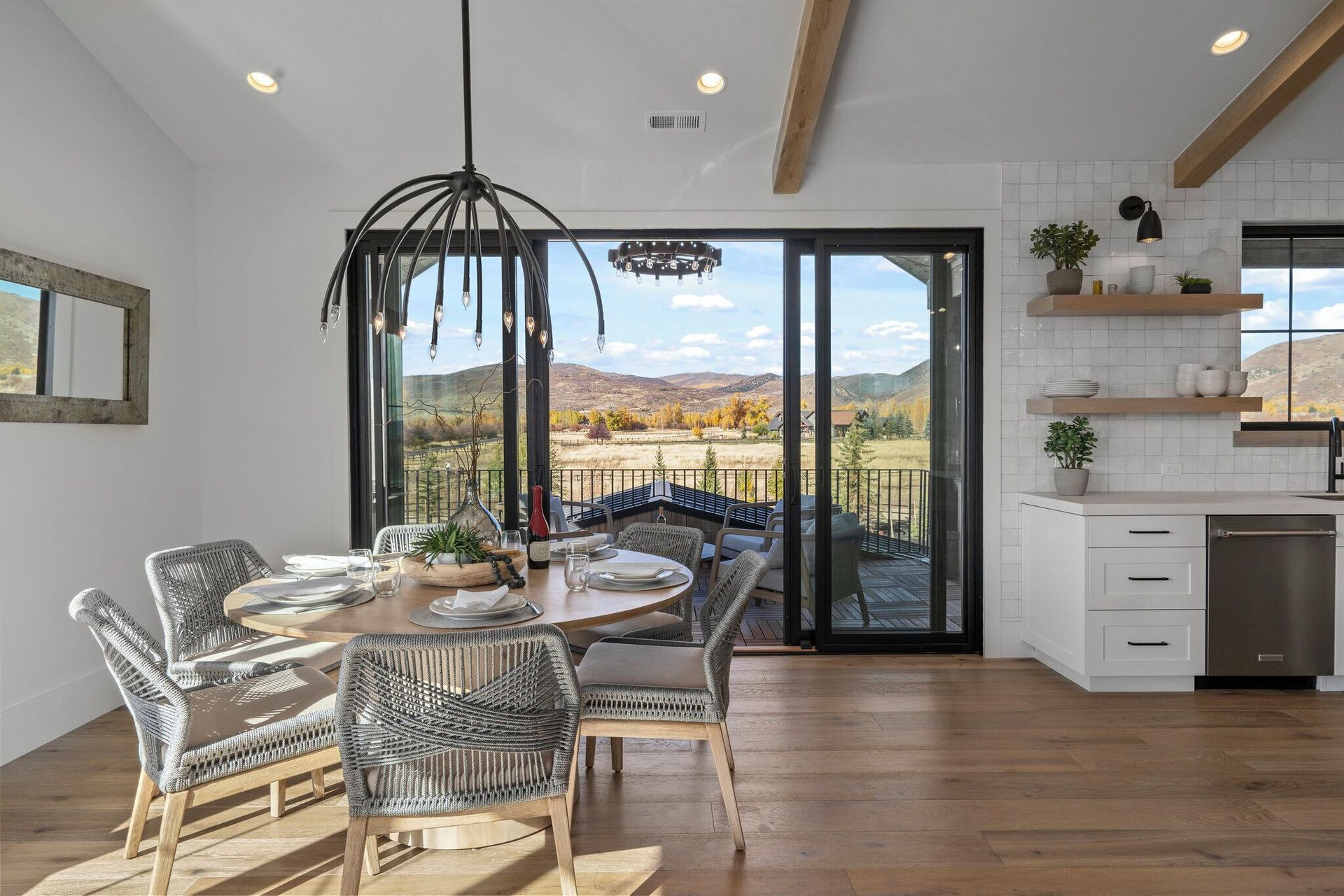 Dining room with round table, chairs, and sliding glass doors opening to a scenic outdoor view.