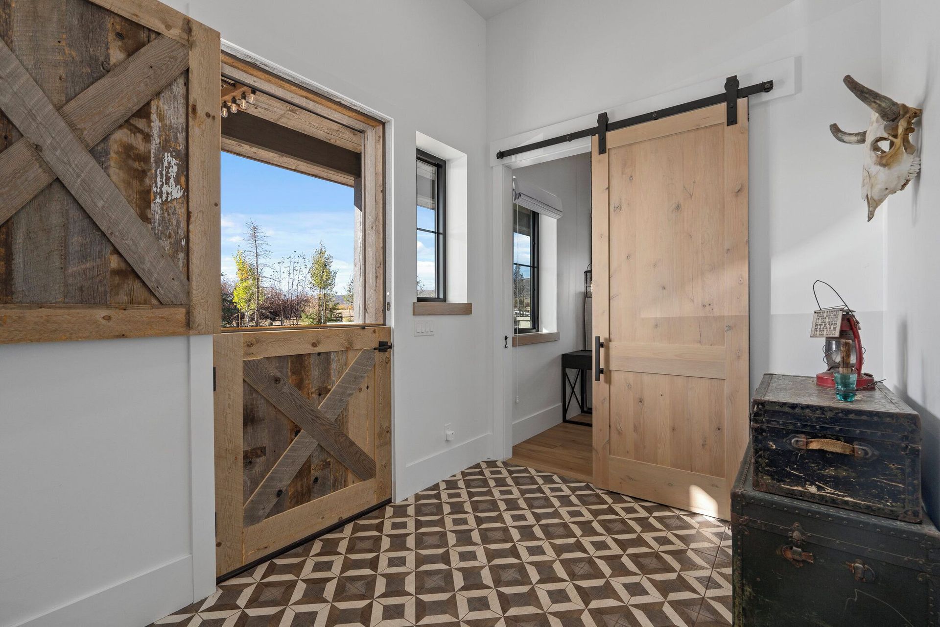 Entryway with rustic barn doors, patterned tile floor, and a distressed chest.