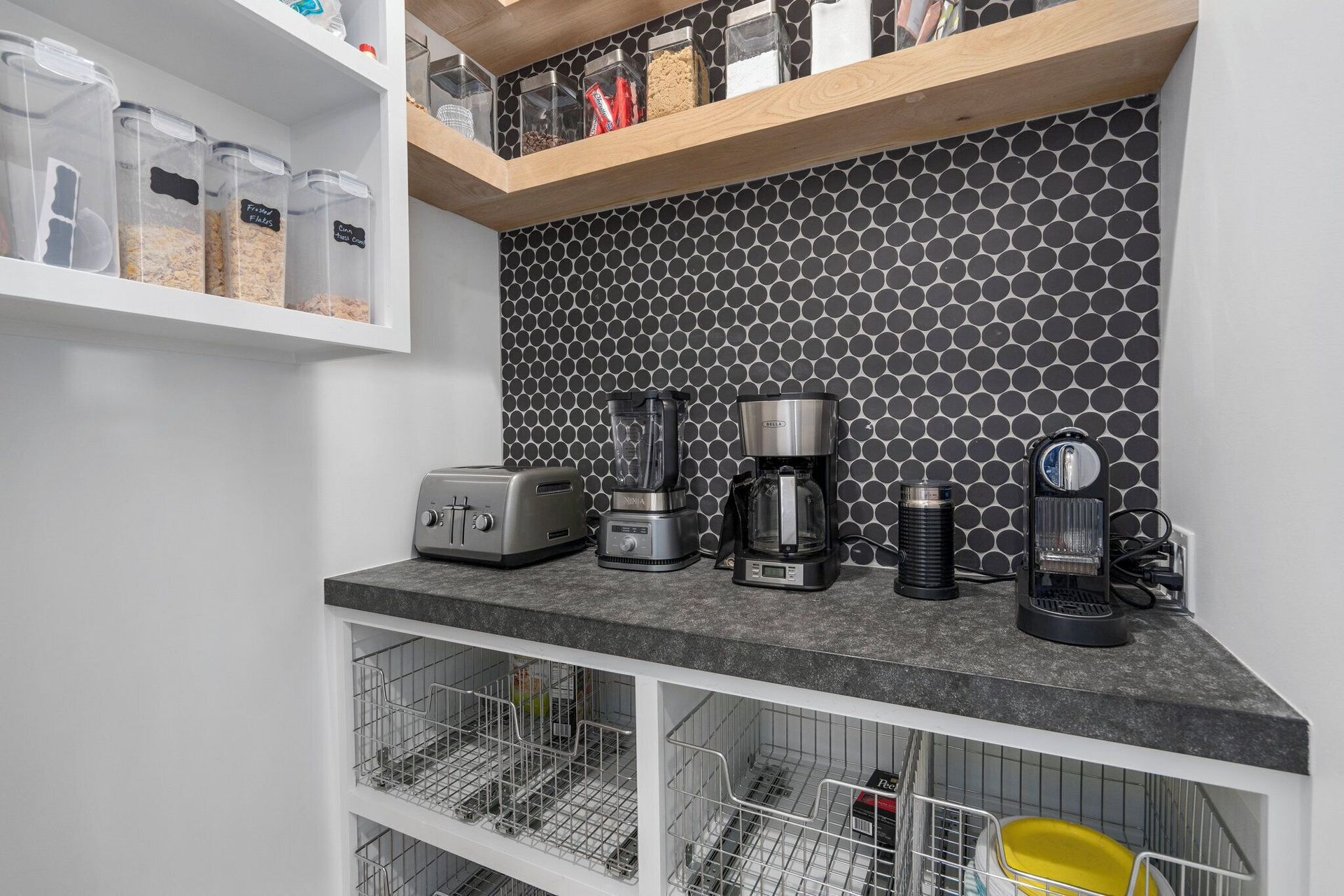 A modern kitchen nook with appliances, a countertop, and storage. Black and white color scheme.