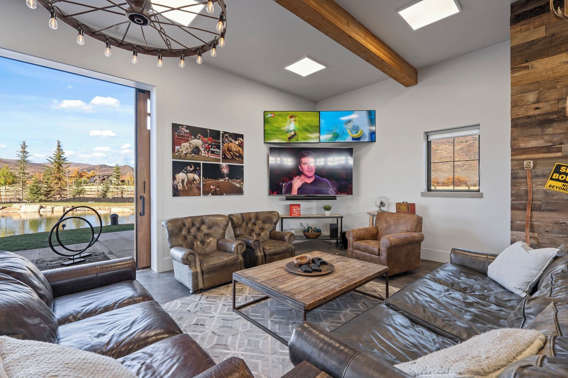 Spacious living room with leather sofas, multiple TVs, and a scenic outdoor view.
