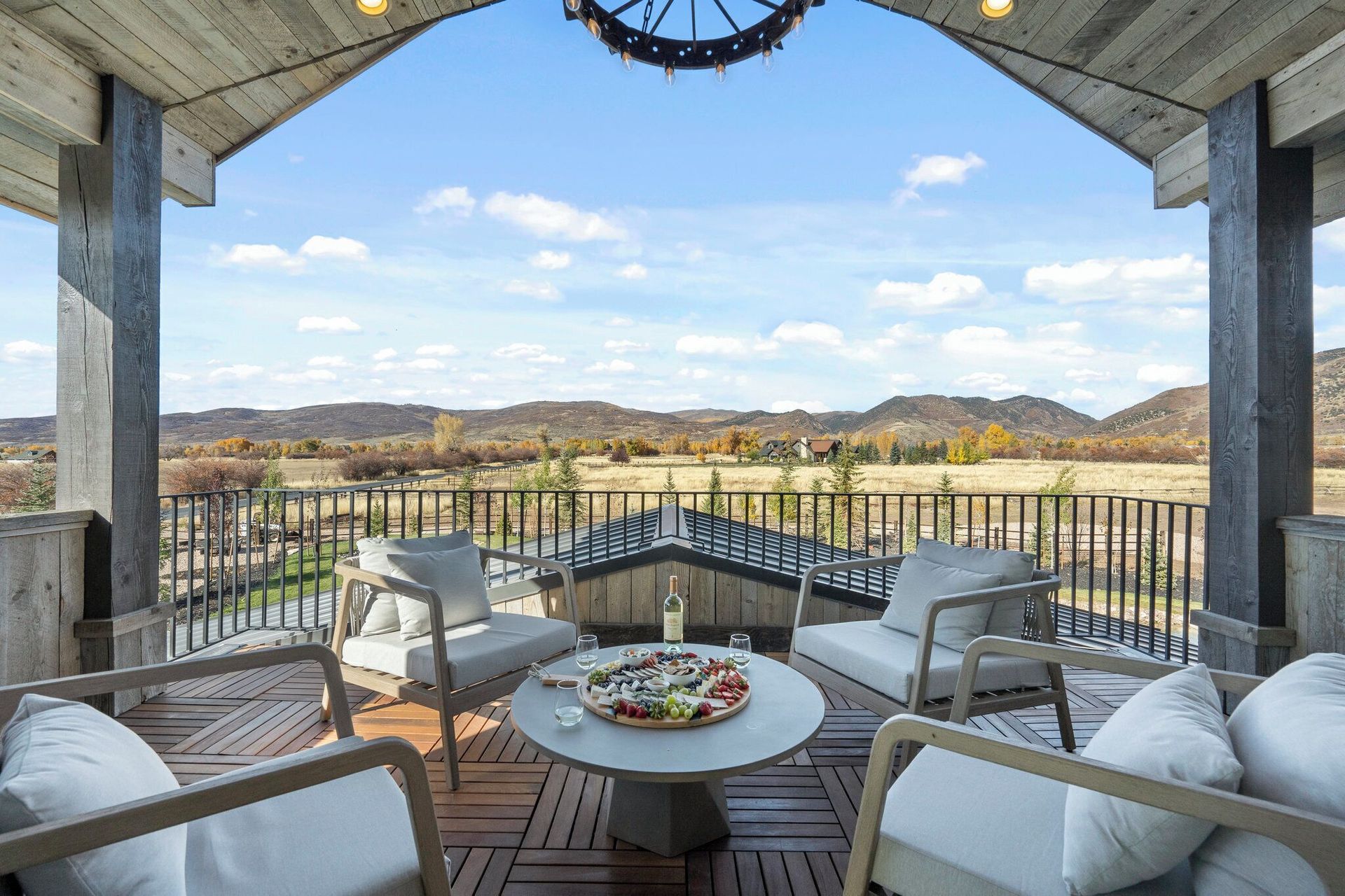 Outdoor patio with seating, a round table with food, and a scenic view of the countryside.