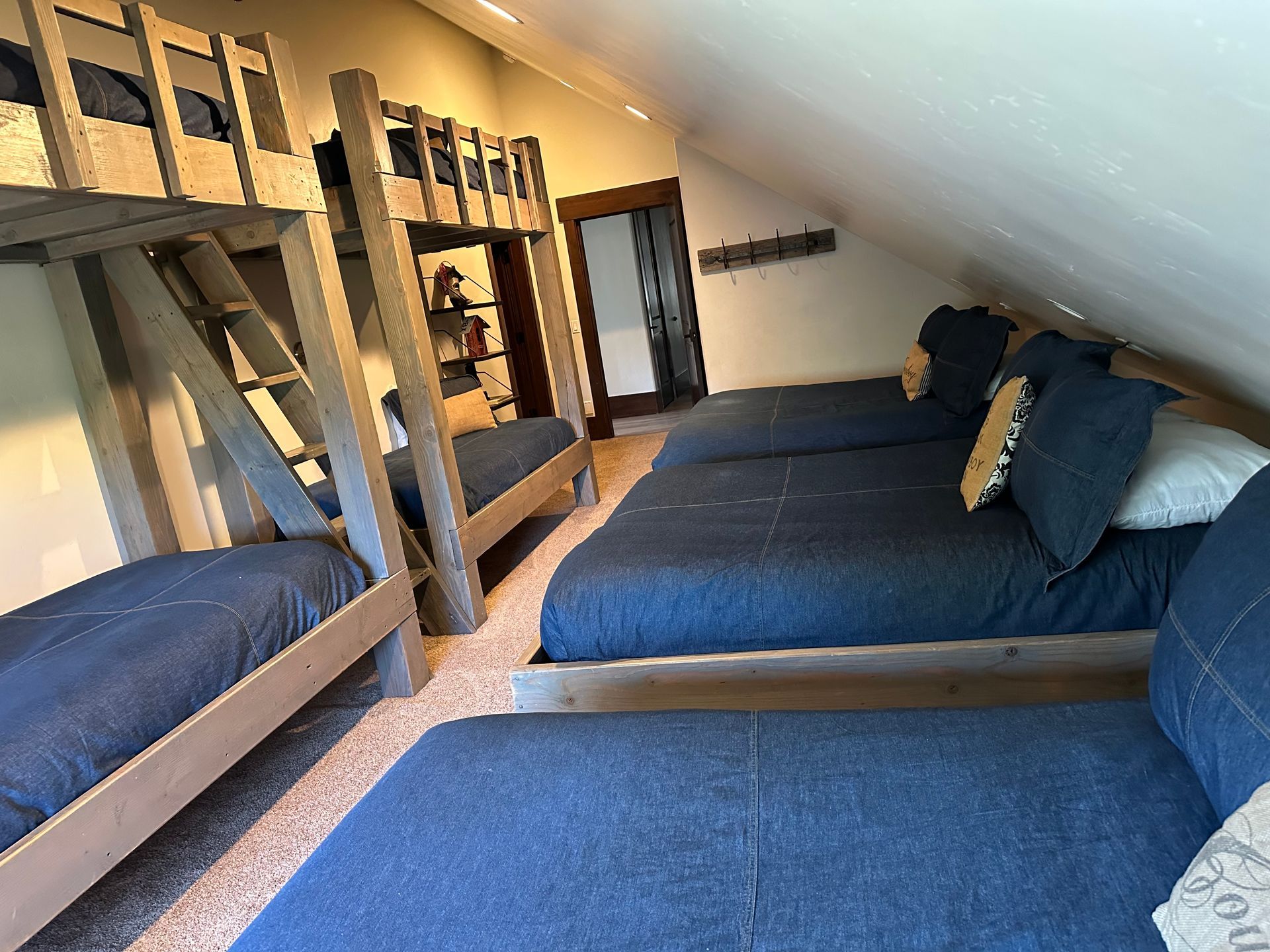 Bedroom with three beds and two sets of bunk beds; angled ceiling; blue bedding.