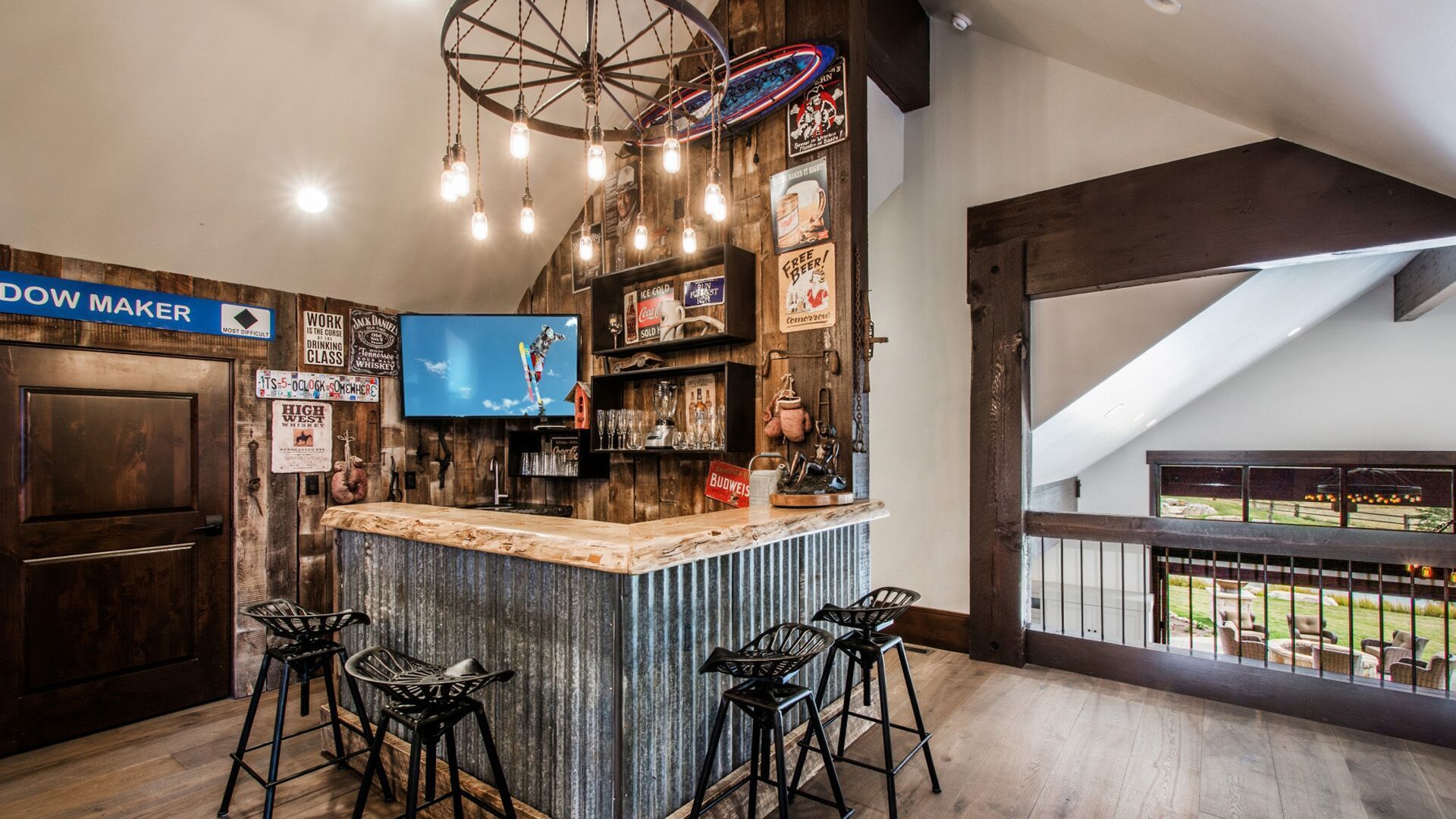 Rustic bar with corrugated metal, wood accents, TV, and motorcycle seat bar stools.