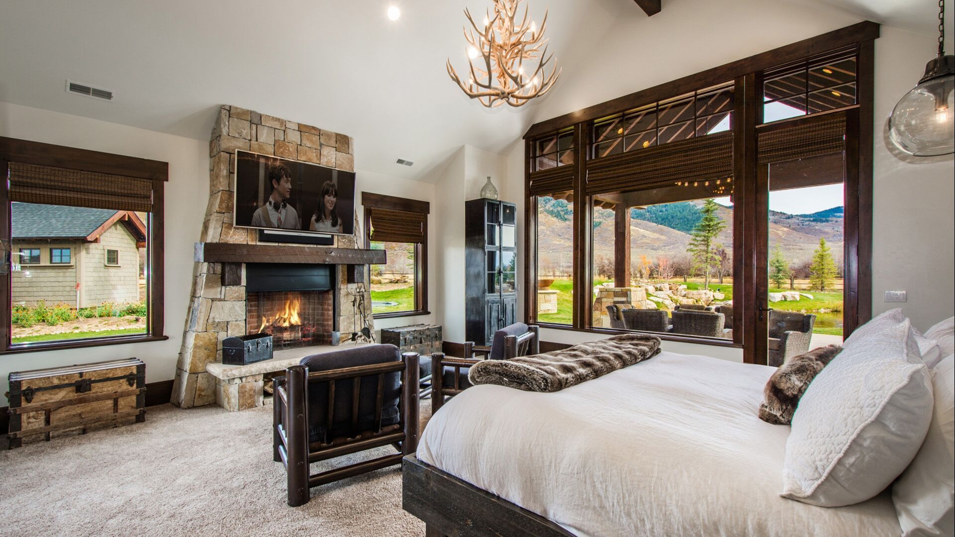 Bedroom with stone fireplace, view of mountains and a bed.