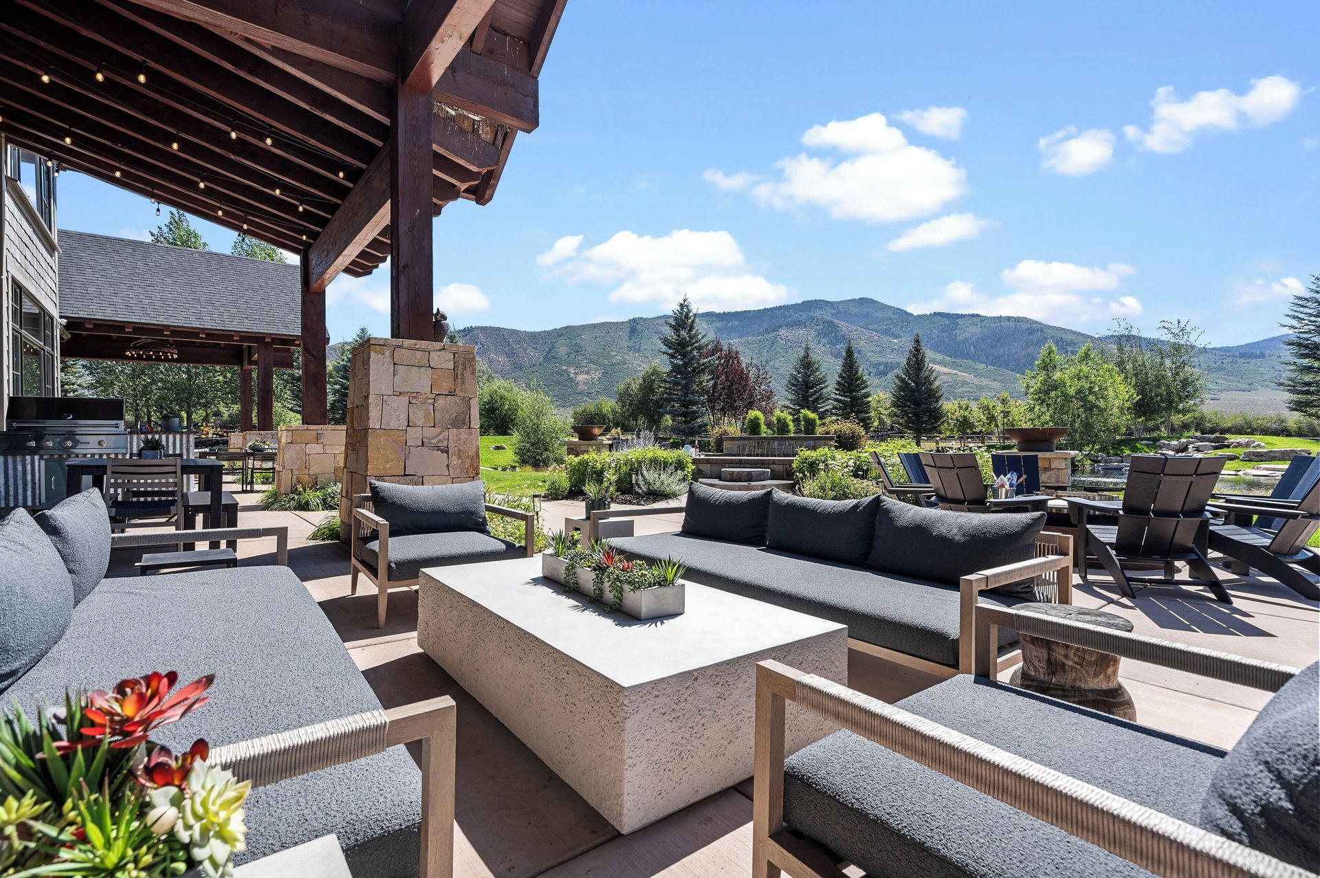 Outdoor patio with gray sofas, a concrete coffee table, and mountain views.