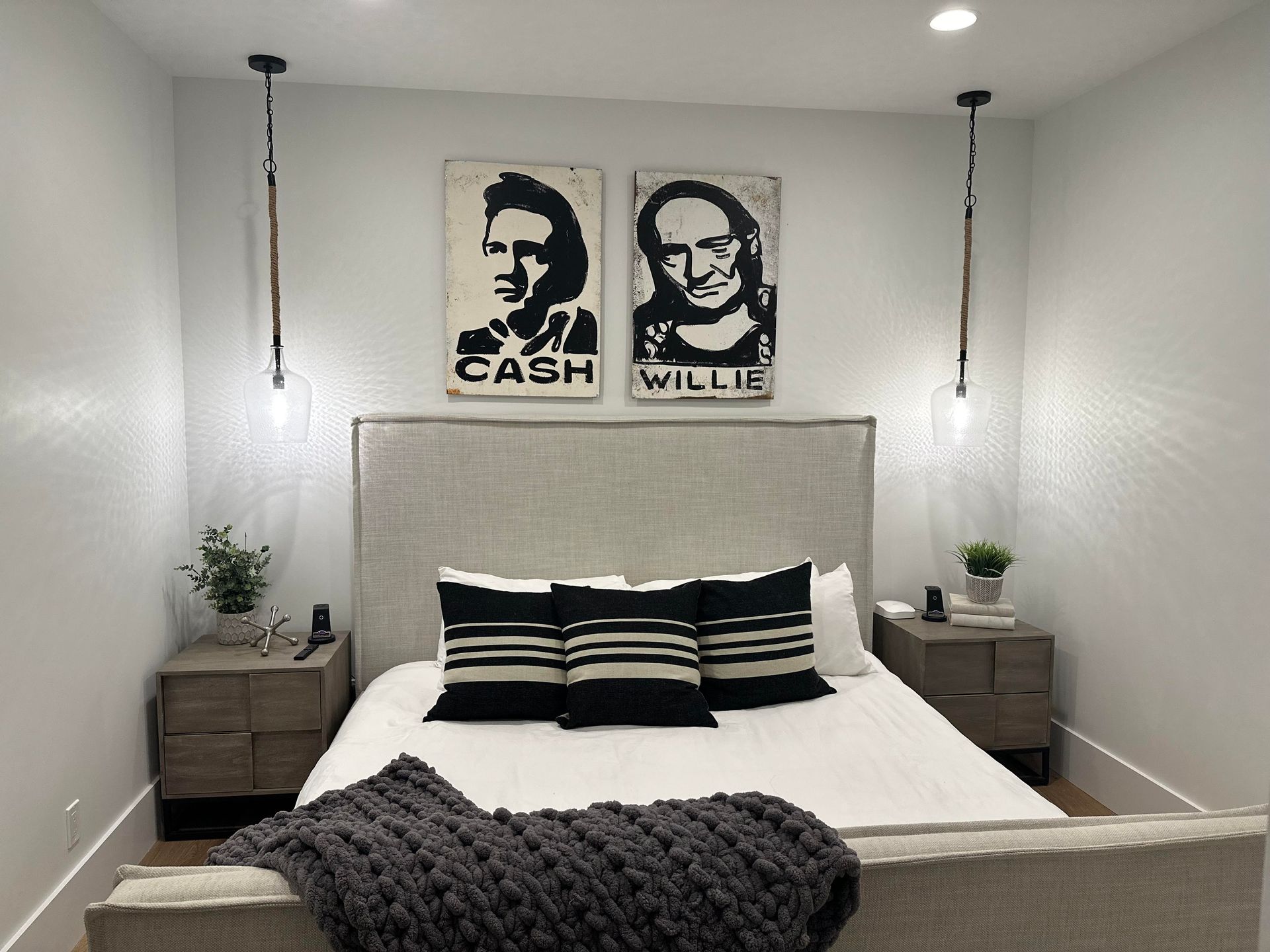 Bedroom with bed, nightstands, and artwork of Johnny Cash and Willie Nelson.