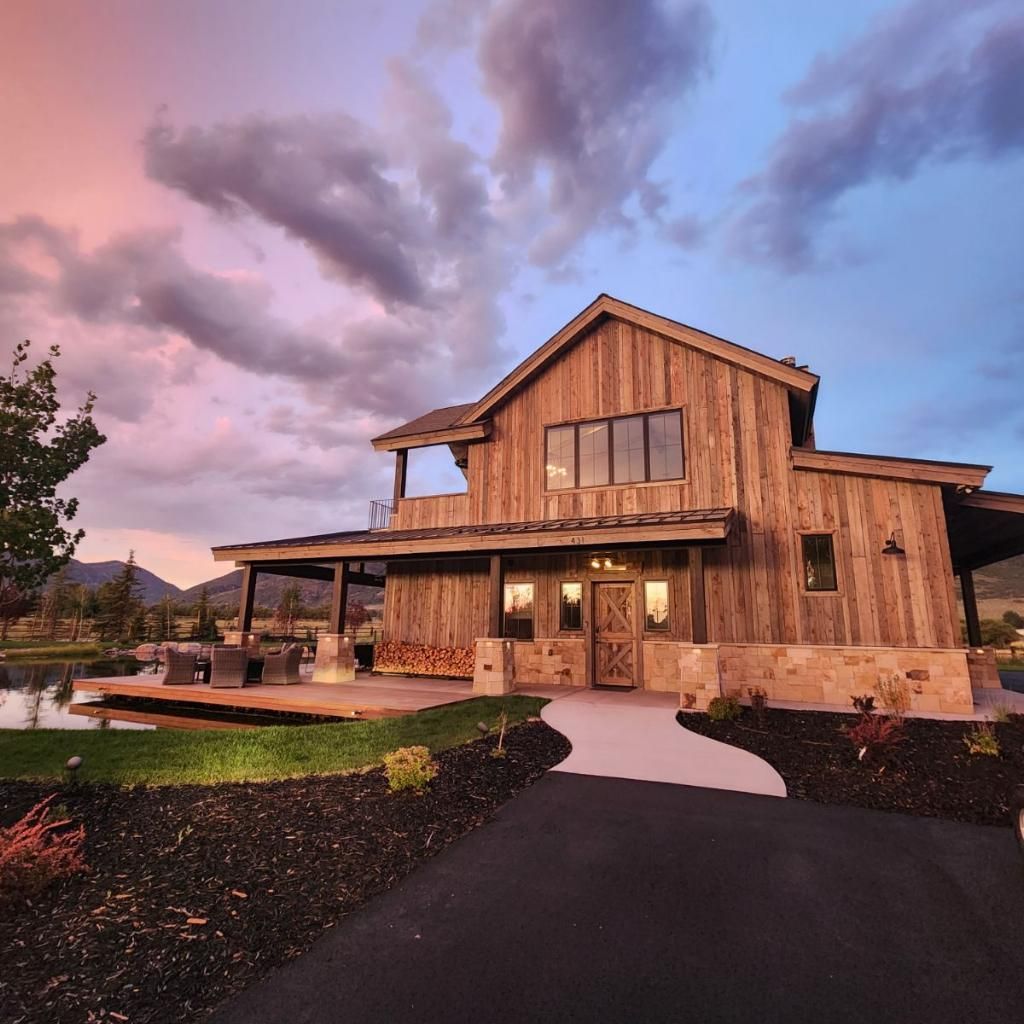Rustic wooden house with a long driveway and a colorful sunset sky.