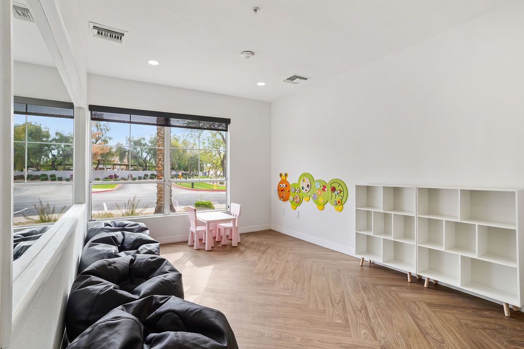 Bright children's playroom with large windows, kid-sized table and cubby shelves.