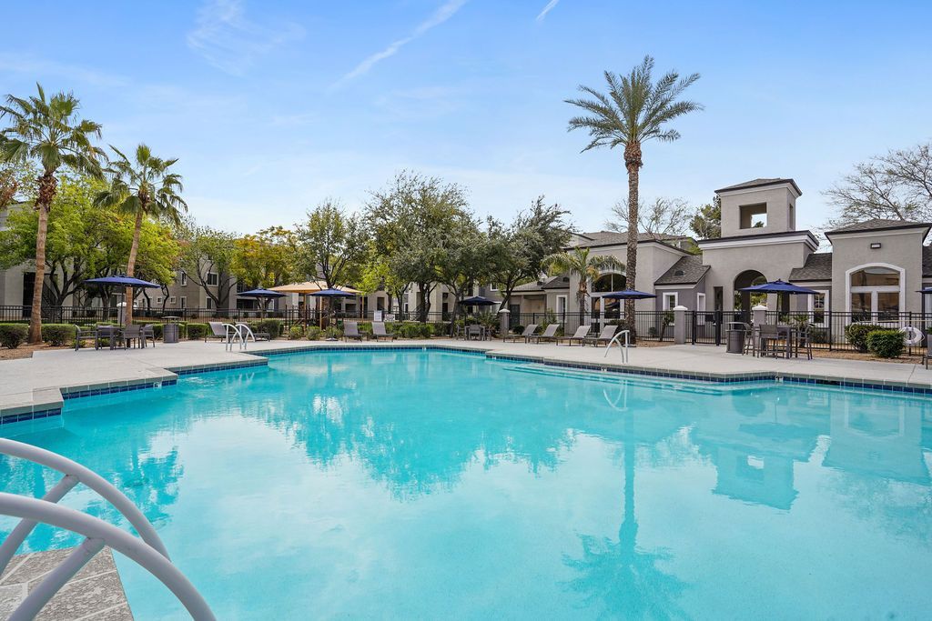 Outdoor apartment community pool with lounge chairs and umbrellas