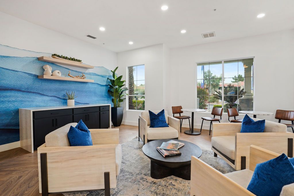 Interior community lounge with blue wave mural, beige seating, and large windows.