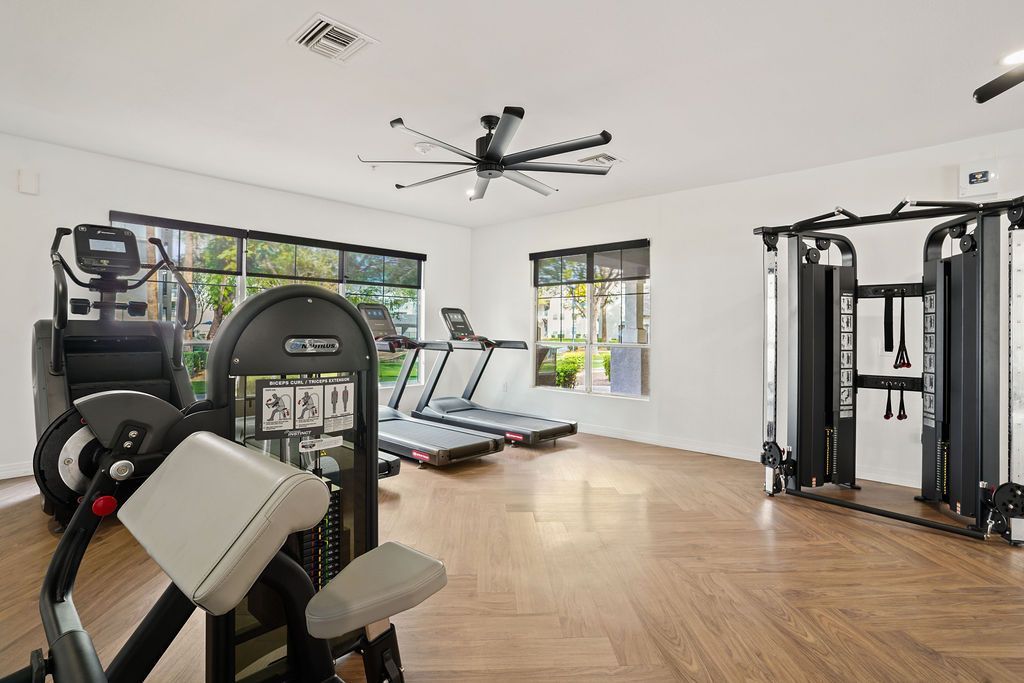 Well-lit community gym with treadmills, cardio machines, and a multi-station weight/cable tower.