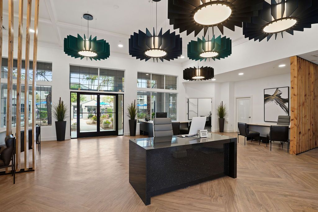 Modern apartment community lobby with a reception desk, seating, and large windows.