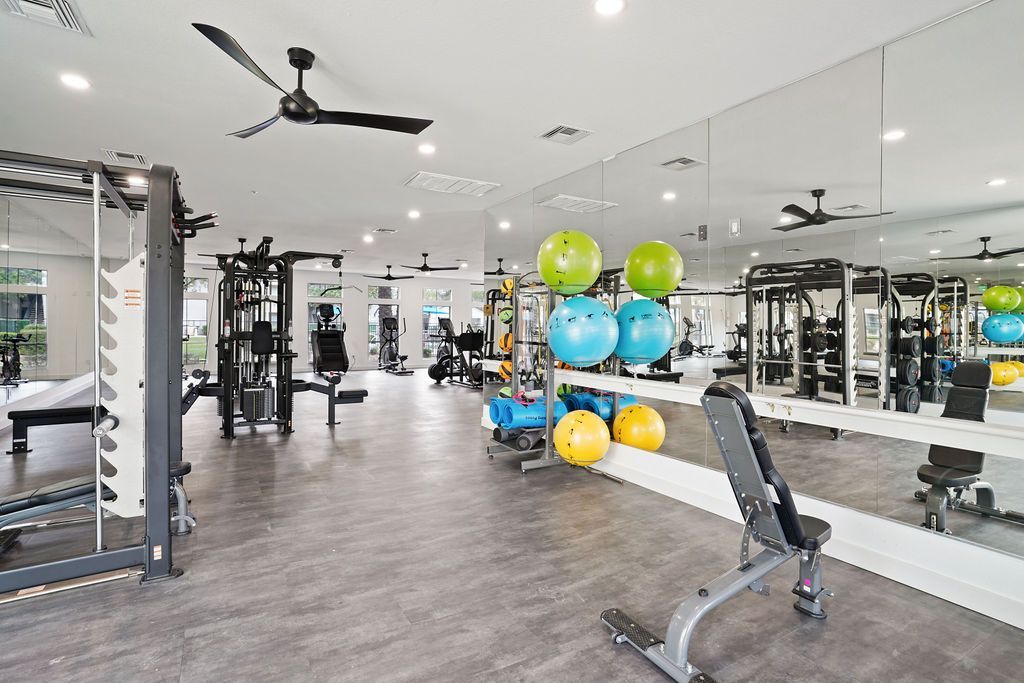 Bright apartment gym with weight machines, free weights, and mirrors.