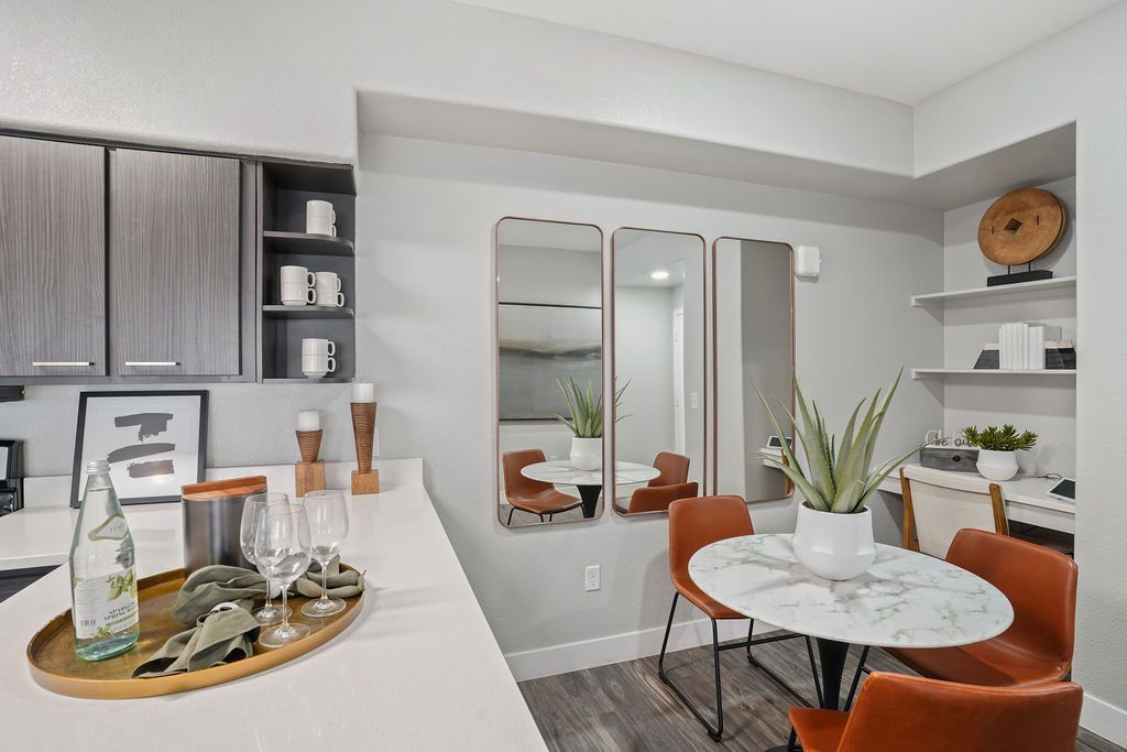 Modern apartment kitchen and dining area with a marble round table and plants.