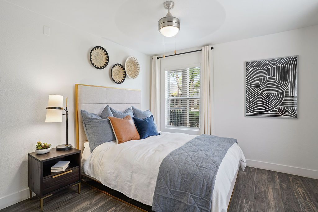 Bedroom with a large bed, nightstand, window, and abstract wall art.