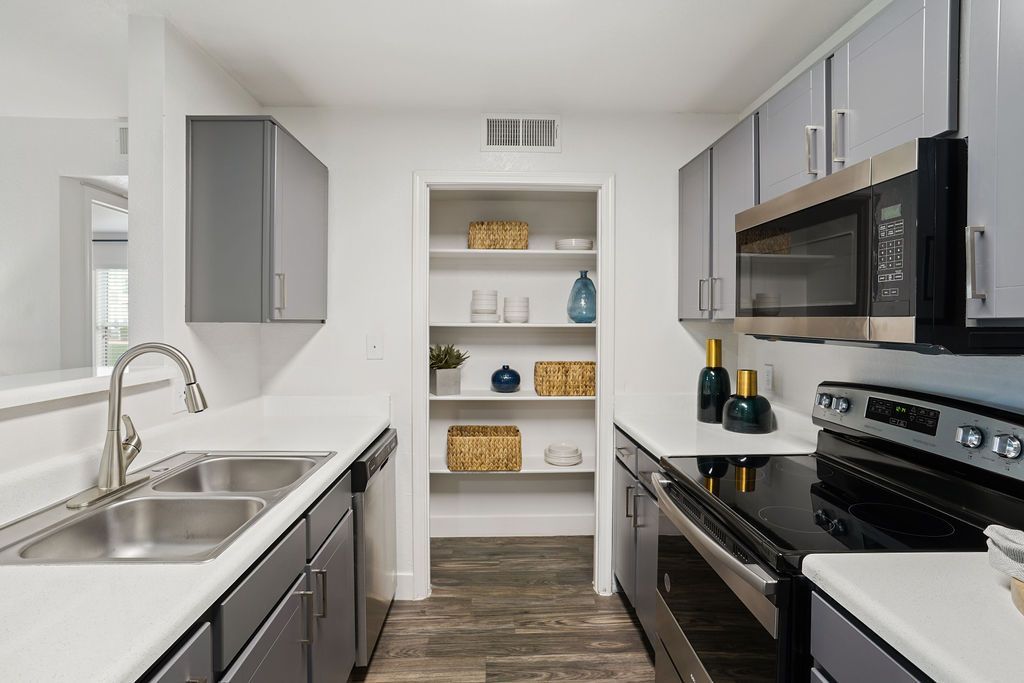 Modern apartment kitchen with a double sink, stainless appliances, and open pantry shelves.