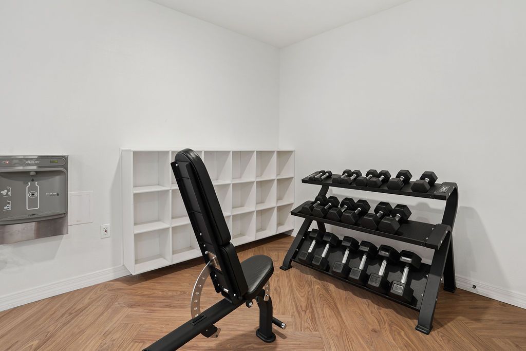 Fitness room with bench, dumbbell rack, and cubby storage.