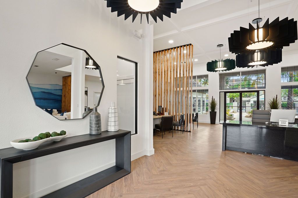 Modern apartment lobby with reception desk, large mirror, and pendant lights.
