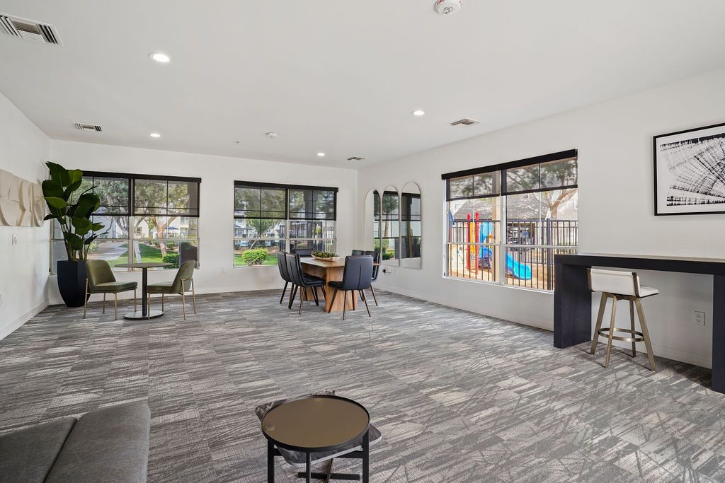 Bright communal lounge with windows, multiple seating areas, and a bar-height counter.