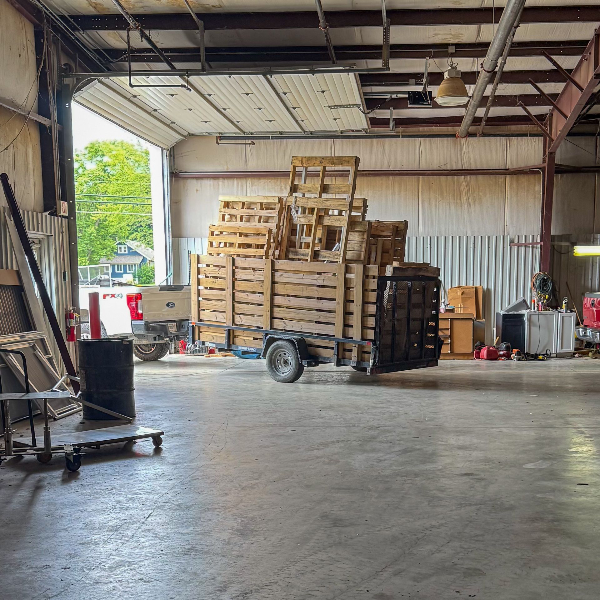 Warehouse interior with trailer loaded with wooden pallets. Open loading door reveals exterior.