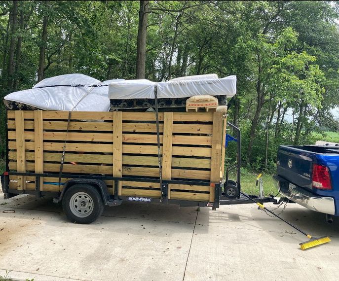 A blue truck is pulling a trailer filled with wooden pallets.