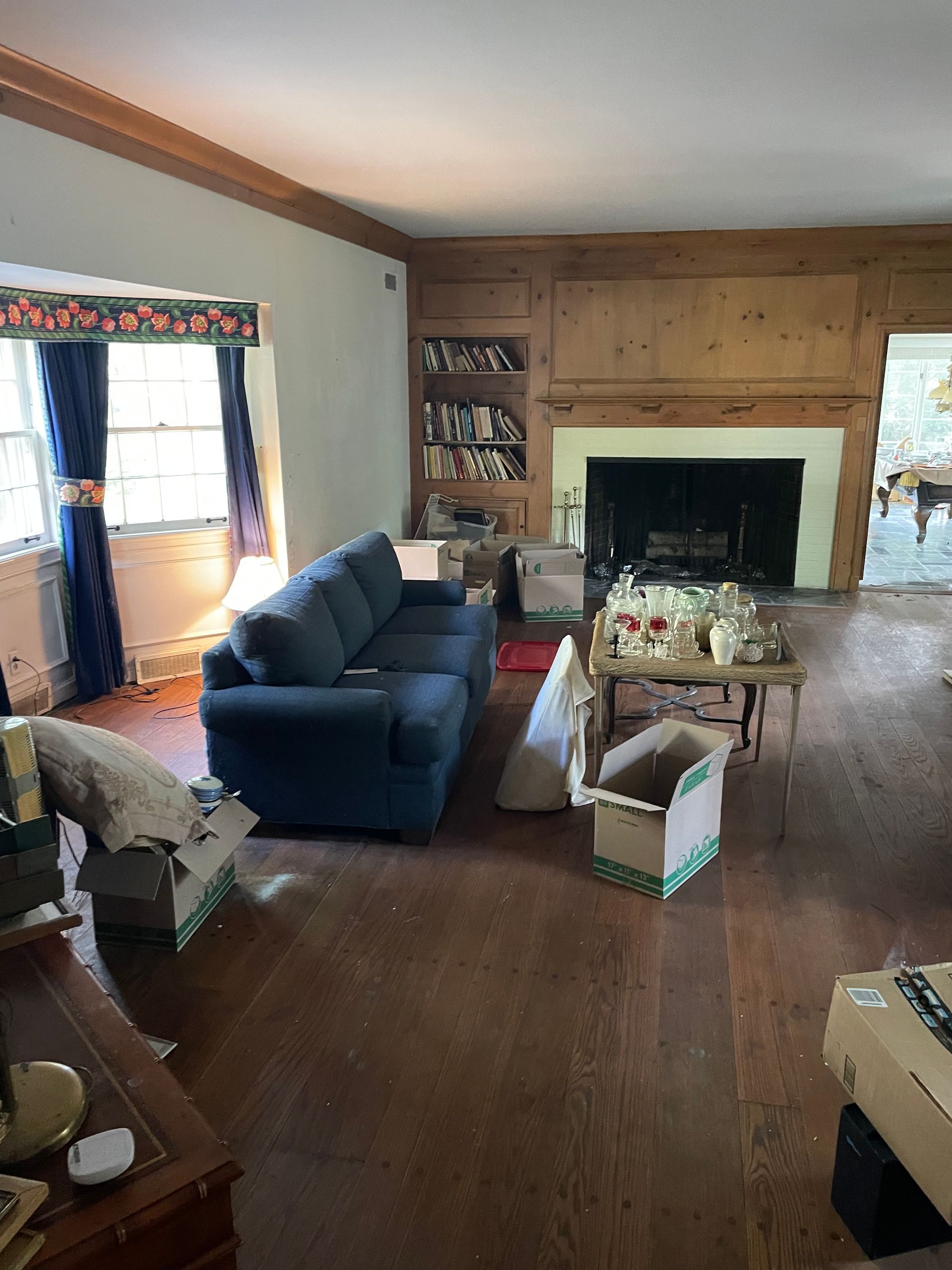 Living room with hardwood floors, sofa, and fireplace; boxes scattered about.
