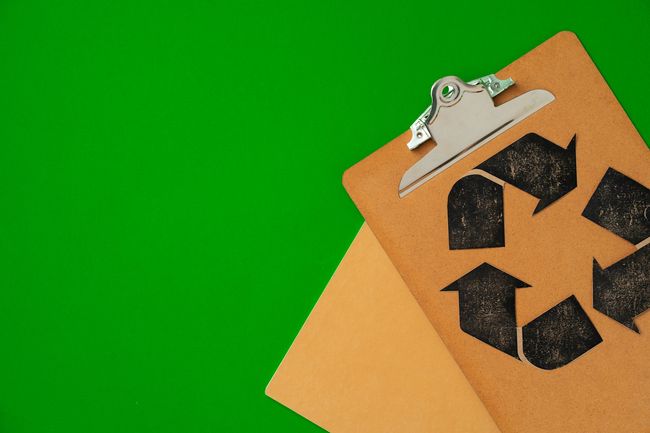 A clipboard with a recycling symbol on it on a green background.