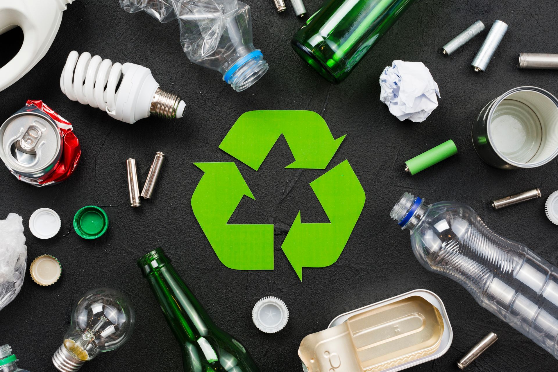 A recycling symbol is surrounded by a variety of recycling items.