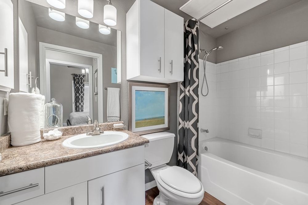 Apartment bathroom with a toilet, sink, and bathtub at Marquis at Texas Street in Dallas, TX.