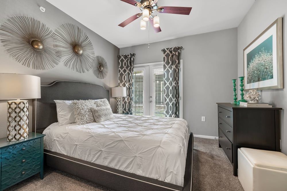 Modern bedroom with a king-size bed, nightstand, dresser, and ceiling fan at Marquis at Texas Street in Dallas, TX.