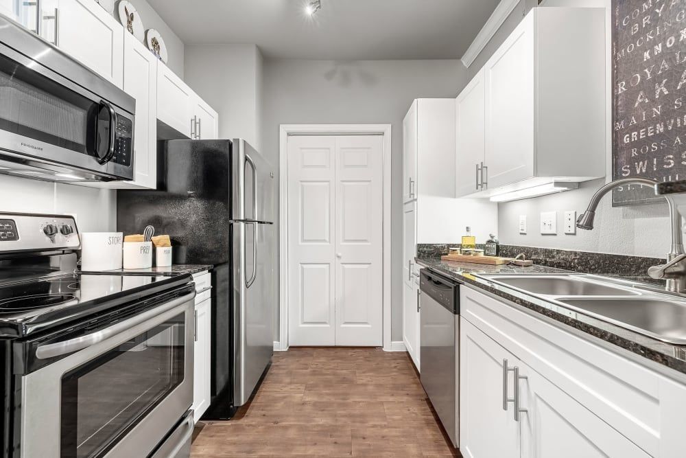Apartment kitchen with stainless steel appliances and white cabinets at Marquis at Texas Street in Dallas, TX.