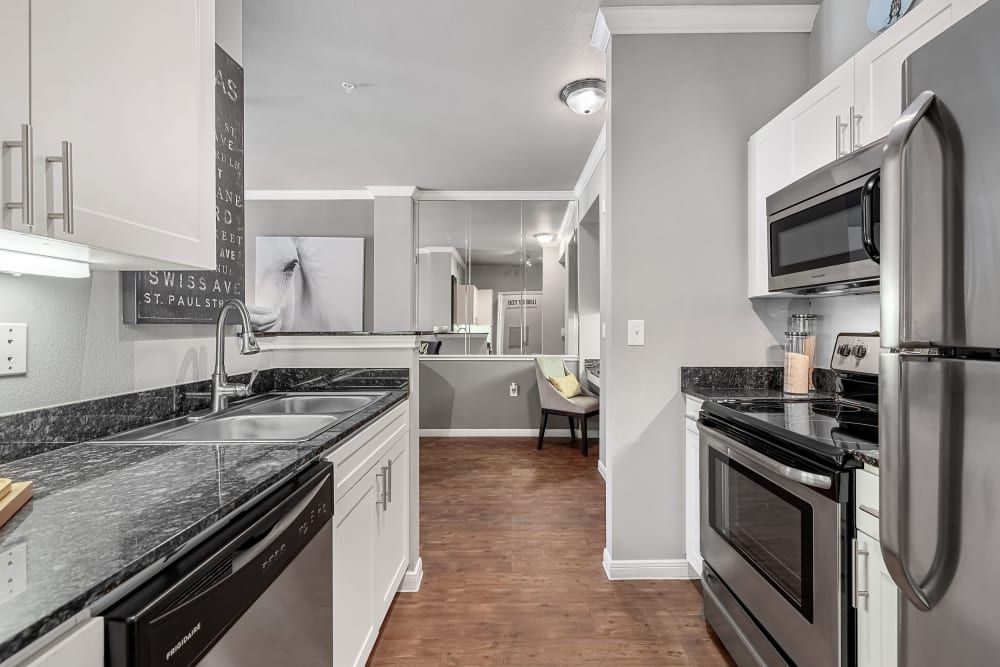 A kitchen with stainless steel appliances and granite counter tops at Marquis at Texas Street in Dallas, TX.