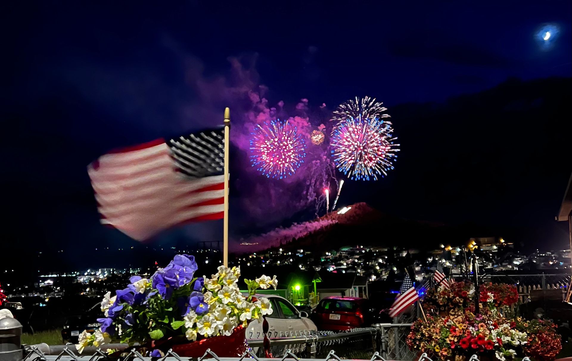 Fireworks exploding in the night sky over  Butte, MT with an american flag in the foreground
