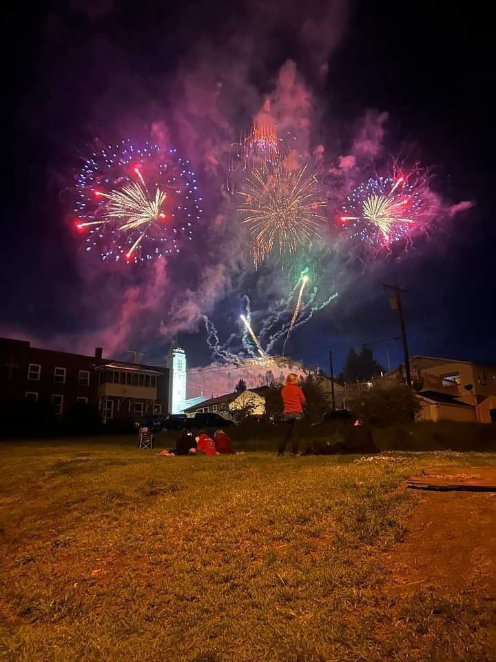 Fireworks exploding in the night sky over  Butte, MT with people in the foreground watching