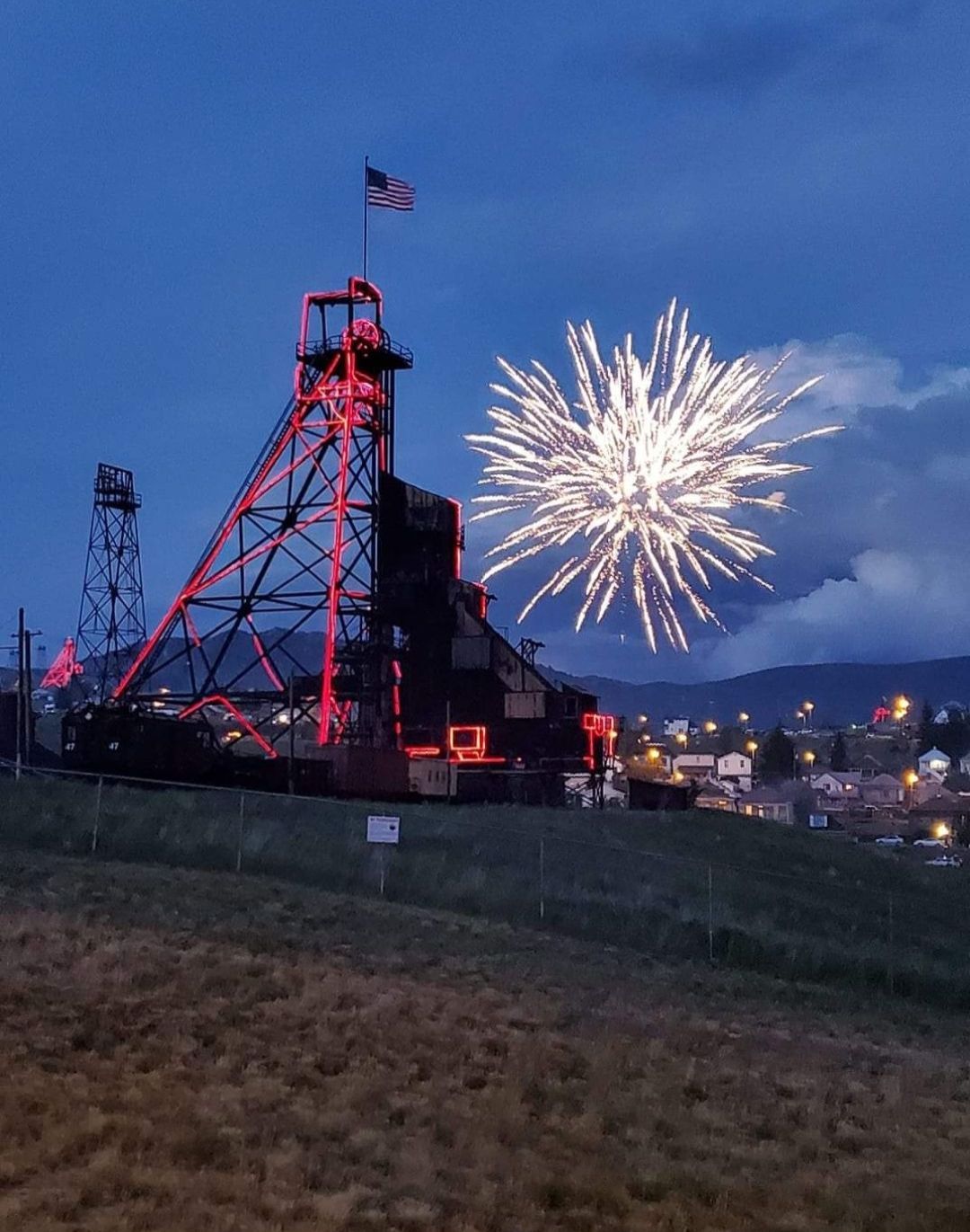 Fireworks exploding in the night sky over  Butte, MT with a headframe in the foreground