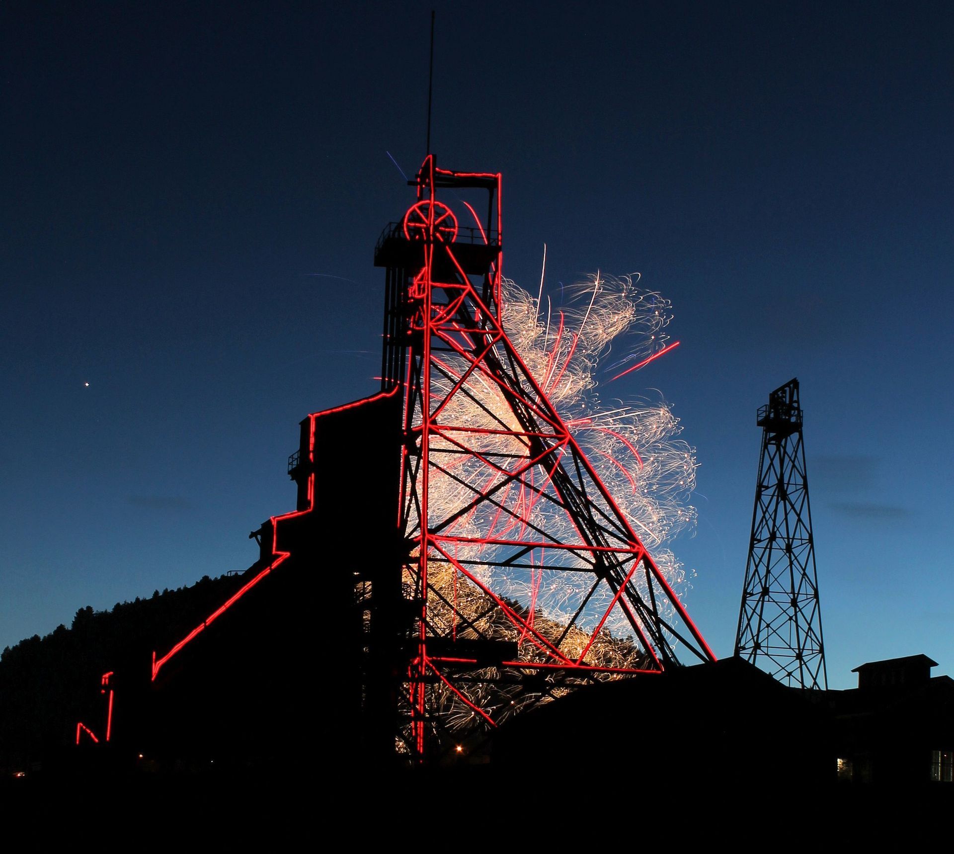 Fireworks exploding at dusk - viewed through a headframe