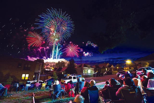Fireworks exploding in the night sky over  Butte, MT with a crowd of observers in the foreground