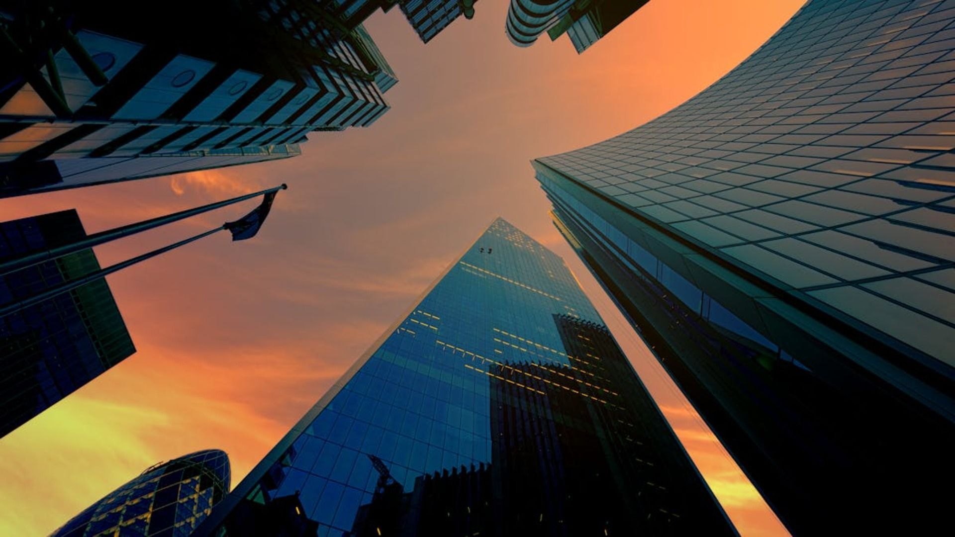 Rascacielos recortados contra una colorida puesta de sol. Edificios de cristal y acero se alzan hacia el cielo.