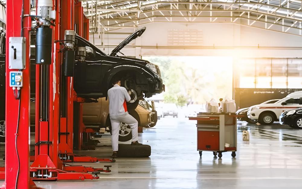 A Man is Working on a Car in a Garage — Docs Mobile Tyre Service In Coolum, QLD