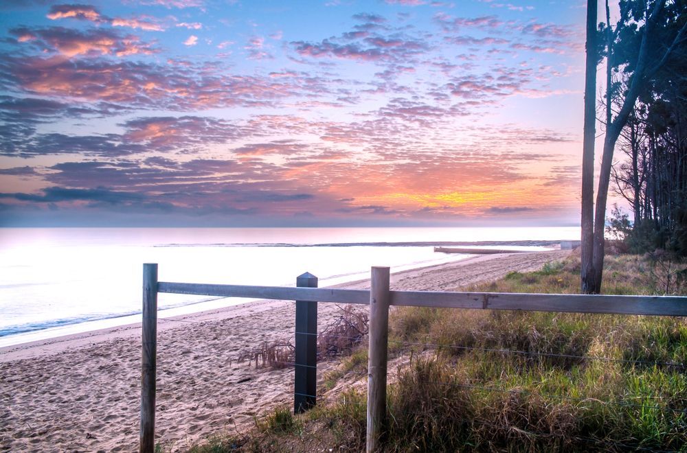 Sunset Over a Calm Beach With a Wooden Fence  — Docs Mobile Tyre Service In Pialba, QLD
