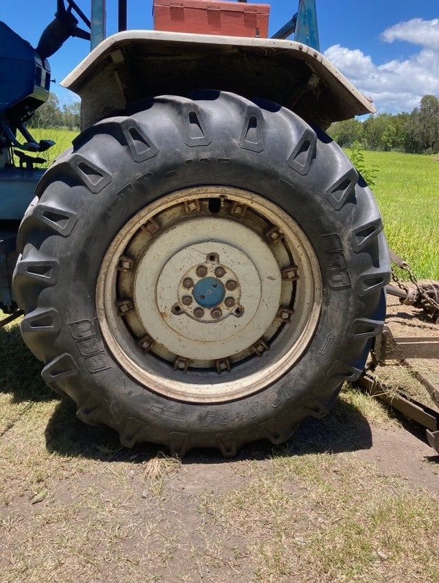 A Tractor With A Large Tire Is Parked In A Field — Docs Mobile Tyre Service in Bli Bli, QLD