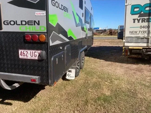 A Caravan is Parked in a Field Next to a Truck — Docs Mobile Tyre Service In Coolum, QLD