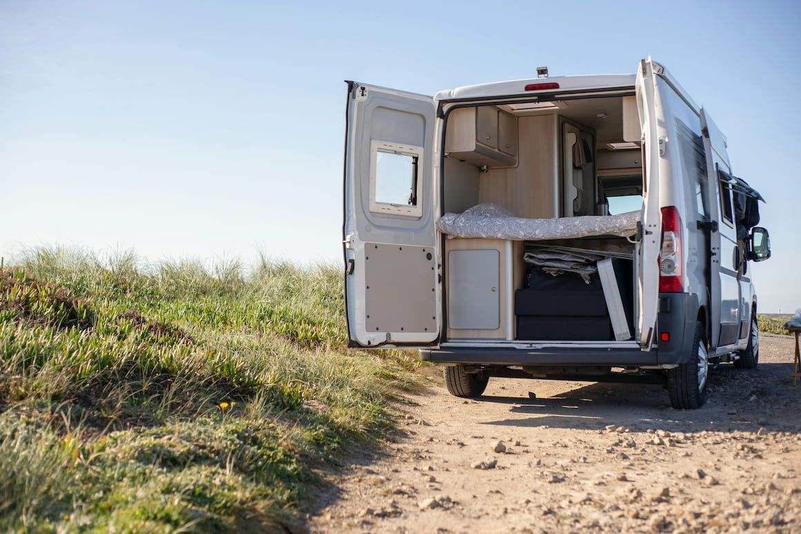 A Camper Van Is Parked on A Dirt Road with Its Doors Open — Docs Mobile Tyre Service in Caloundra, QLD