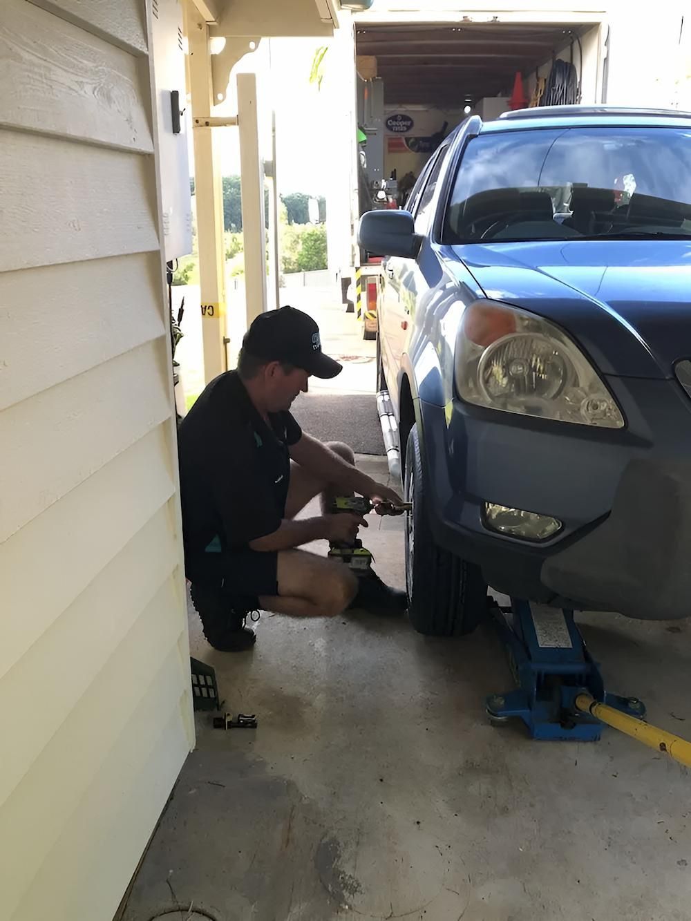 A Man is Working on a Blue Car in a Garage — Docs Mobile Tyre Service In Yandina, QLD