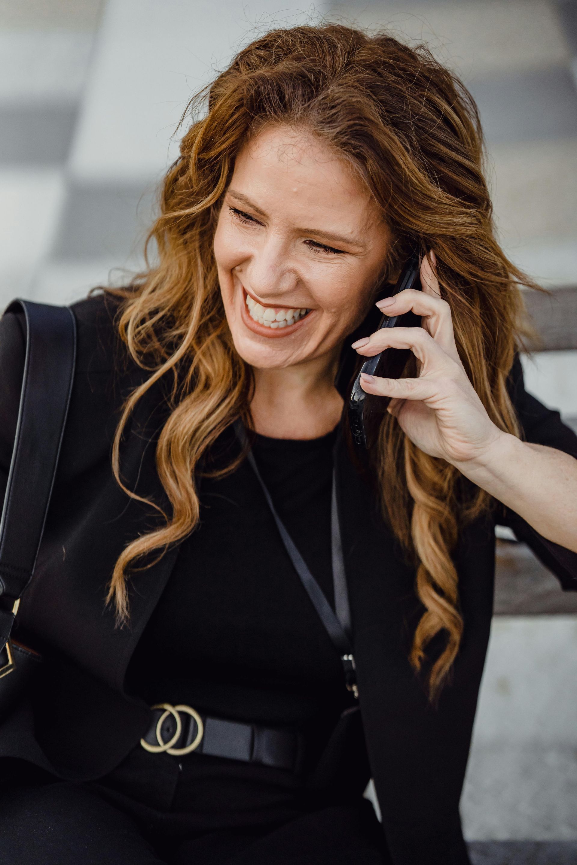 A woman is smiling while talking on a cell phone.