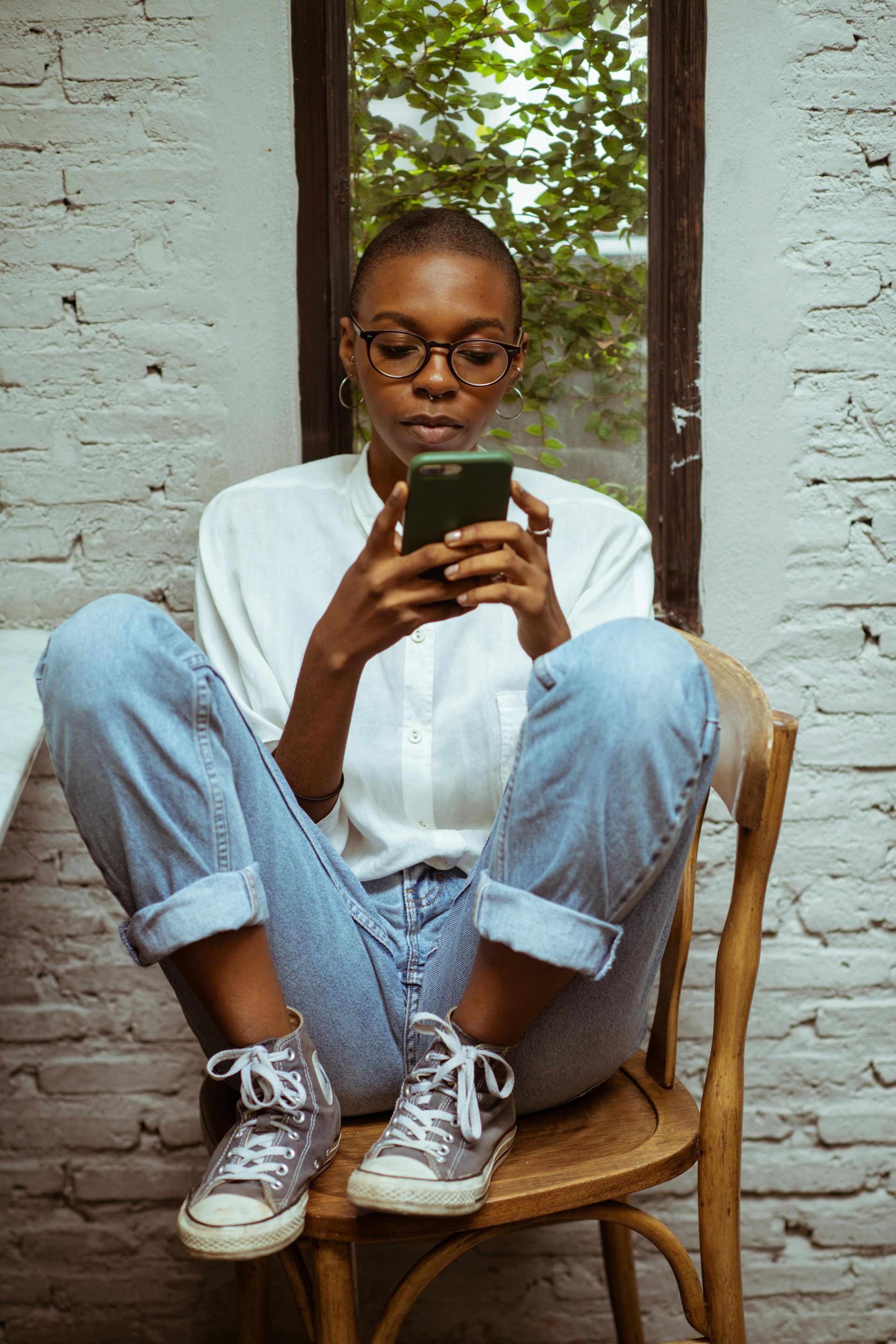 A woman is sitting on a chair looking at her cell phone.