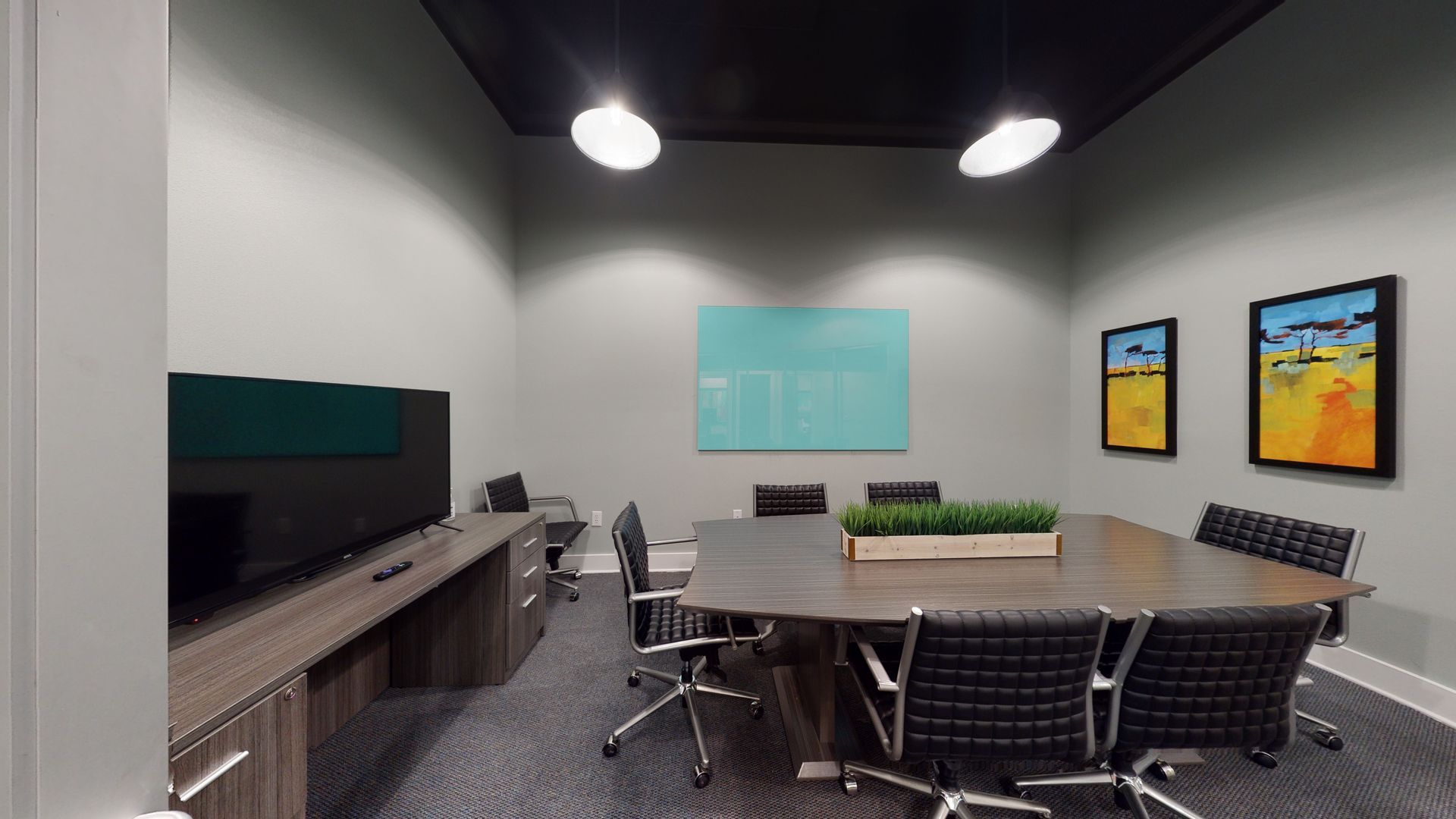 A conference room with a long table and chairs and a television.